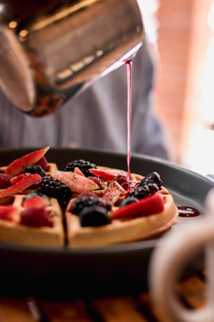 a person pouring syrup on a plate of food