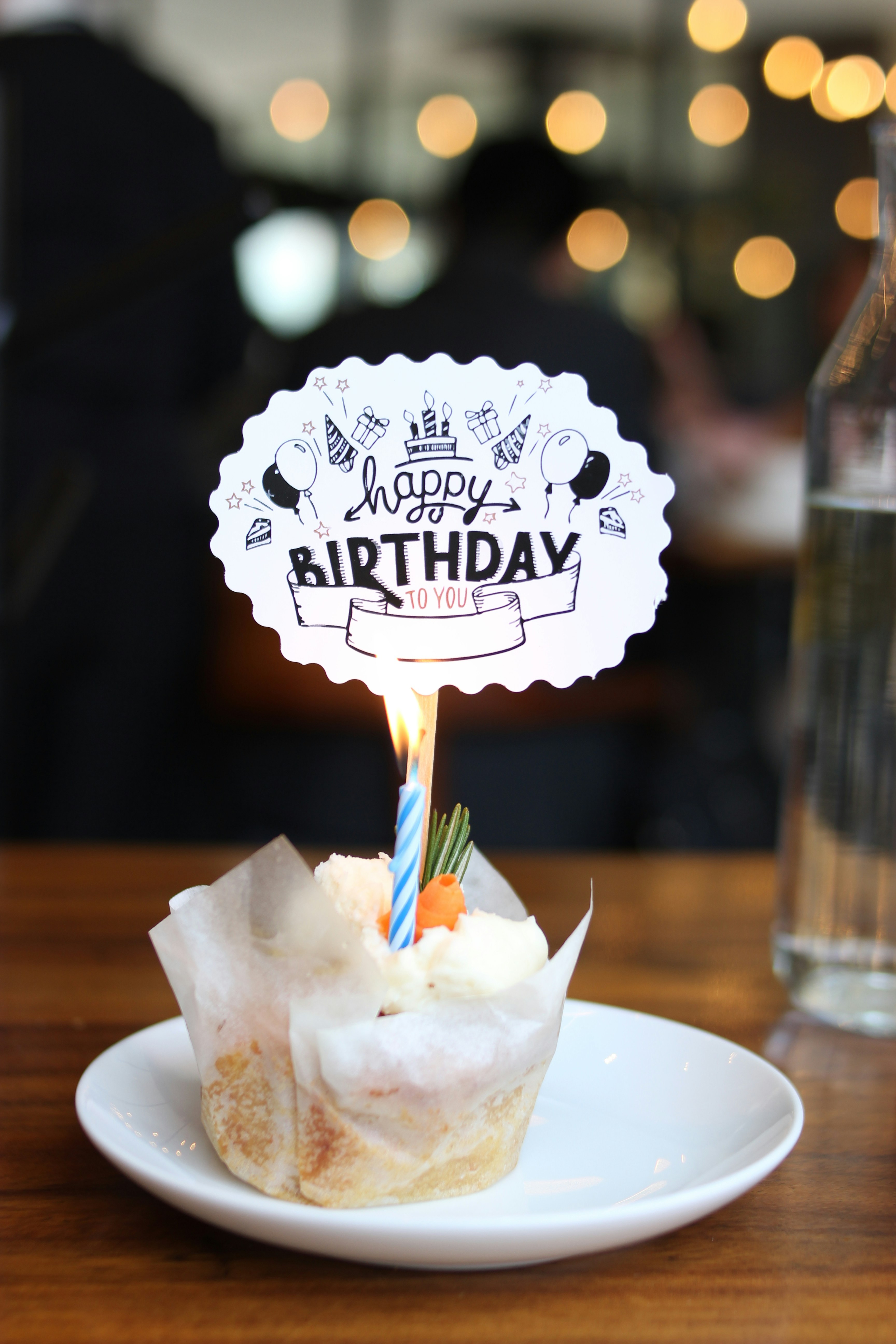 Custom cupcake toppers with name and age on a pastel birthday cake in warm light