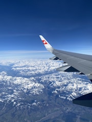A sleek private jet soaring above the Swiss Alps with snow-capped peaks.