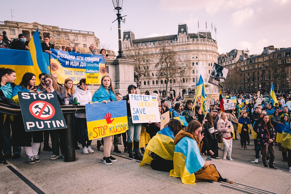 a group of people holding signs and sitting on the ground