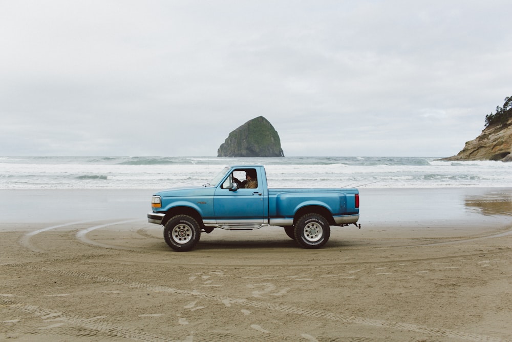 a blue pick up truck parked on the beach