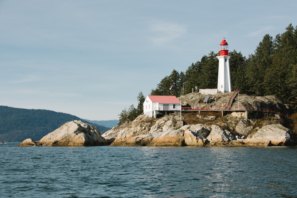 a white and red lighthouse on a rocky island