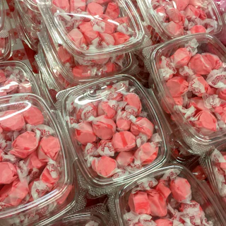 An artful arrangement of assorted candies in clear sachets with pastel pink accents.