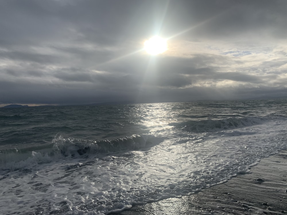 the sun shining through the clouds over the ocean