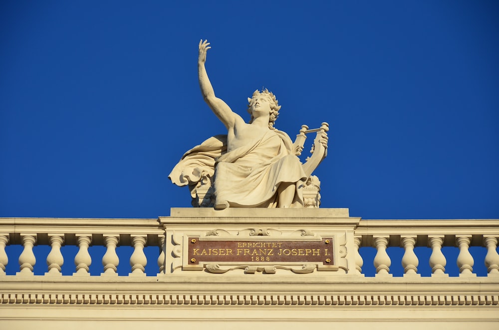 Una estatua en la parte superior de un edificio con un cielo azul en el fondo