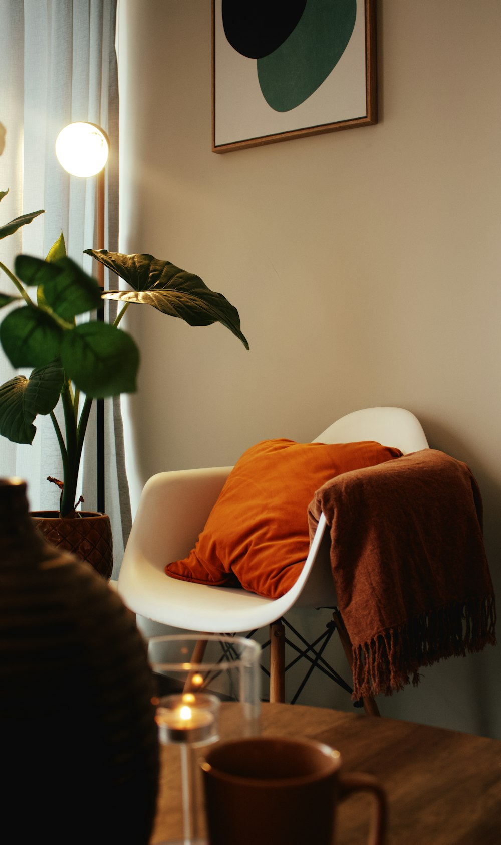 a chair with a blanket on it next to a potted plant