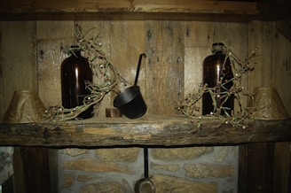 Shiny copper bottles glistening under soft light on a rustic shelf.