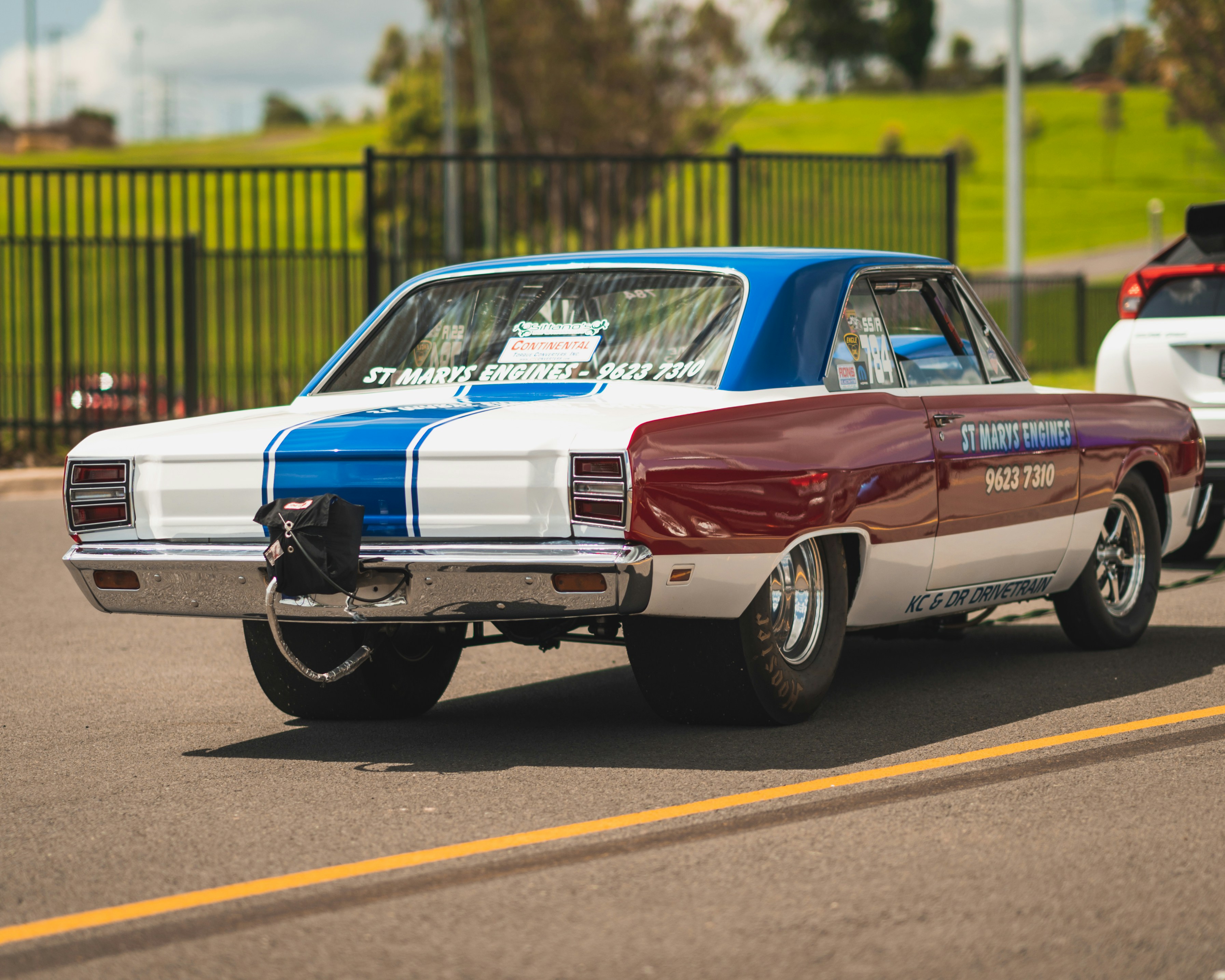 um carro azul e branco dirigindo por uma rua
