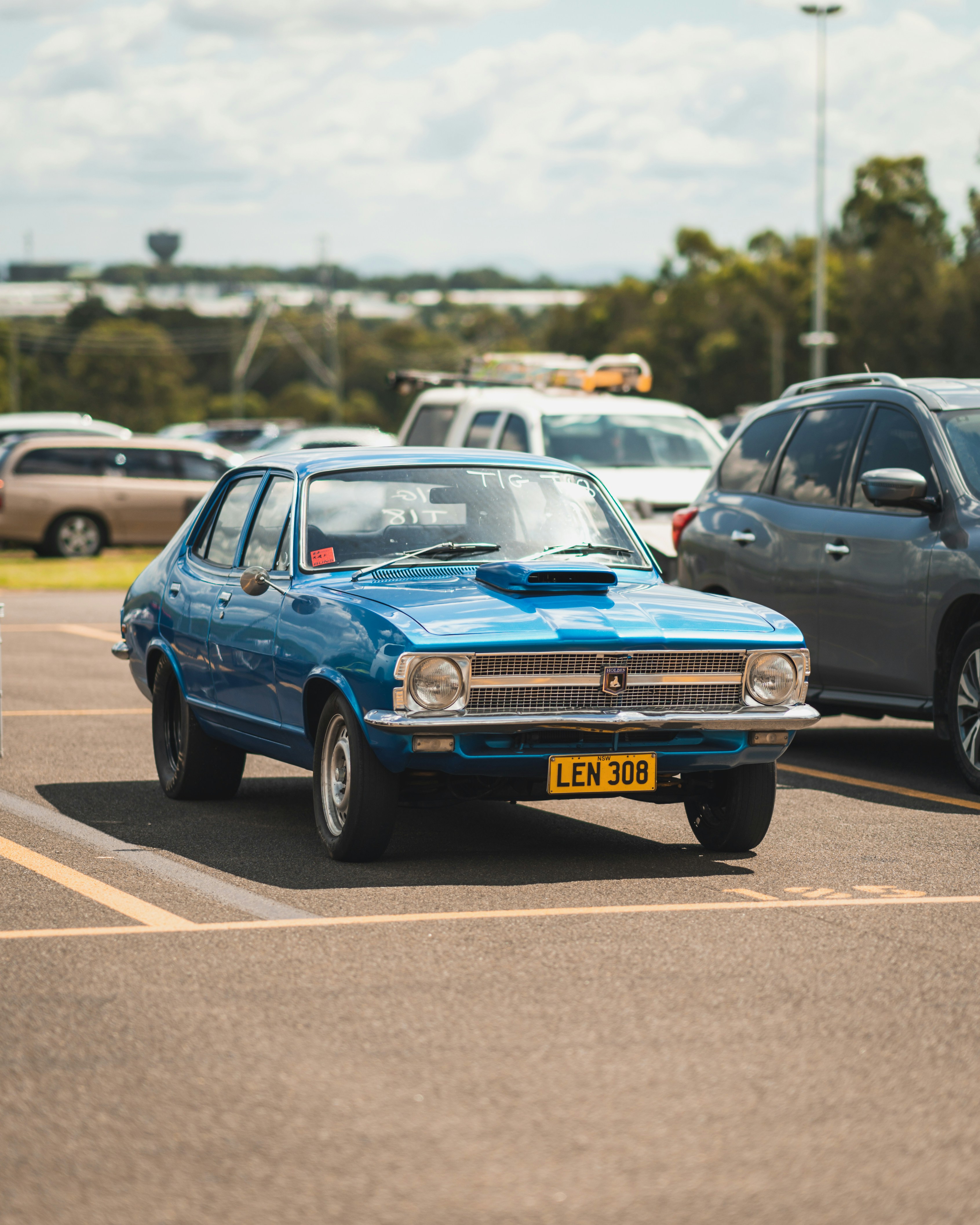 um carro azul estacionado em um estacionamento ao lado de outros carros