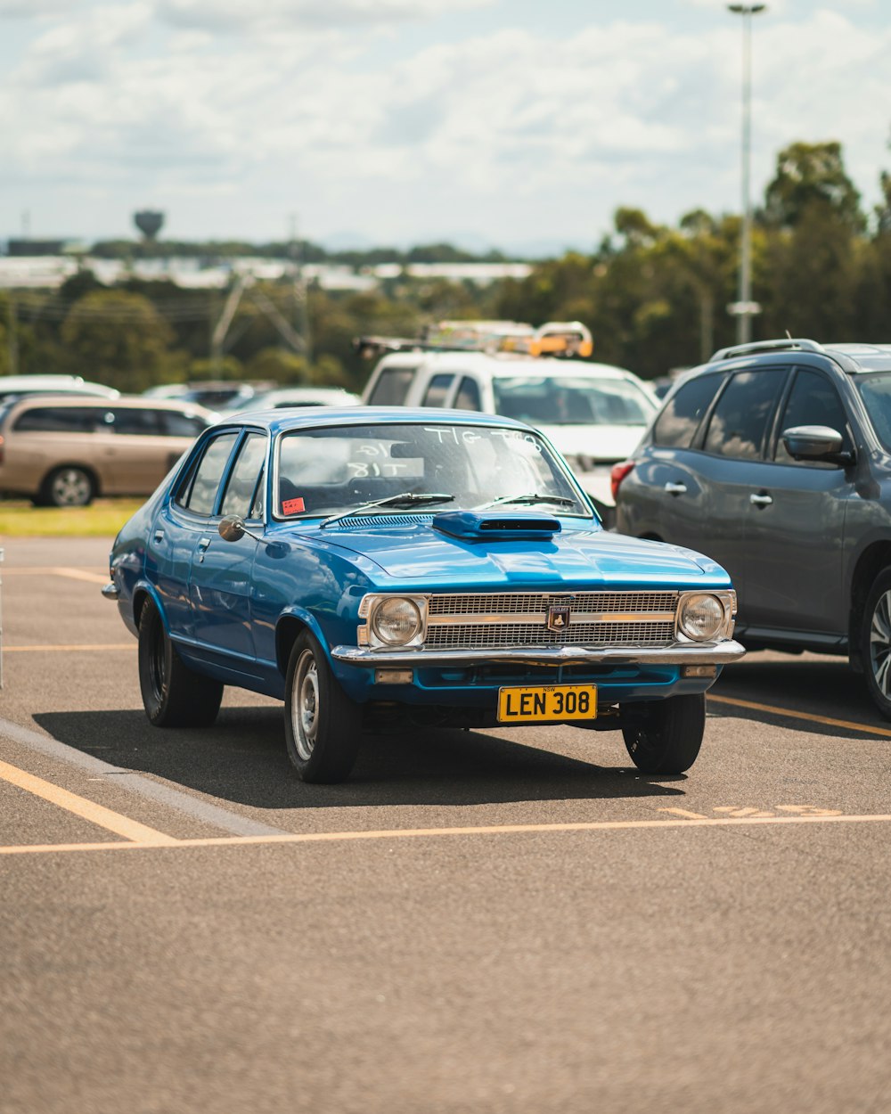 a blue car parked in a parking lot next to other cars