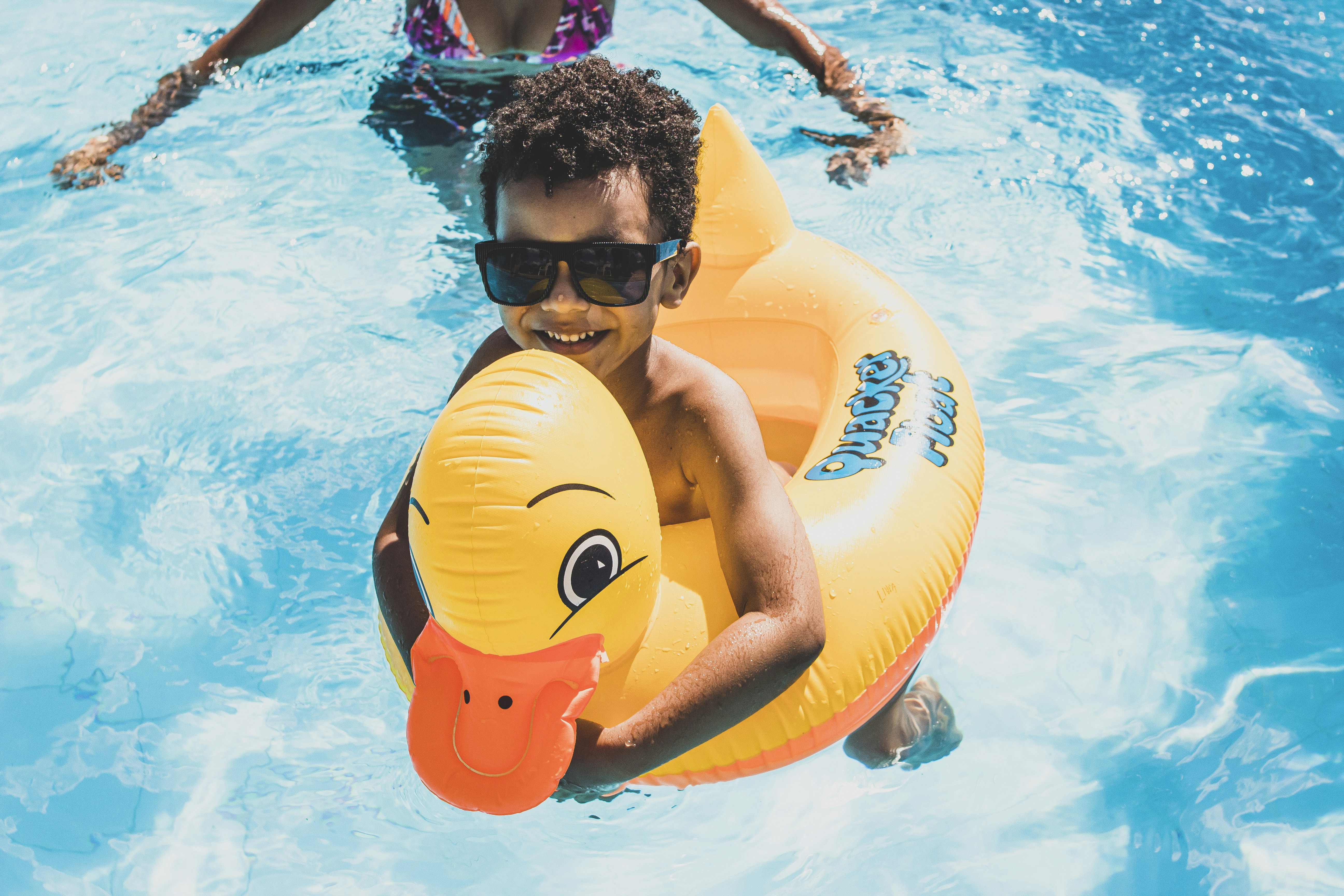 a boy in a swimming pool holding an inflatable ducky