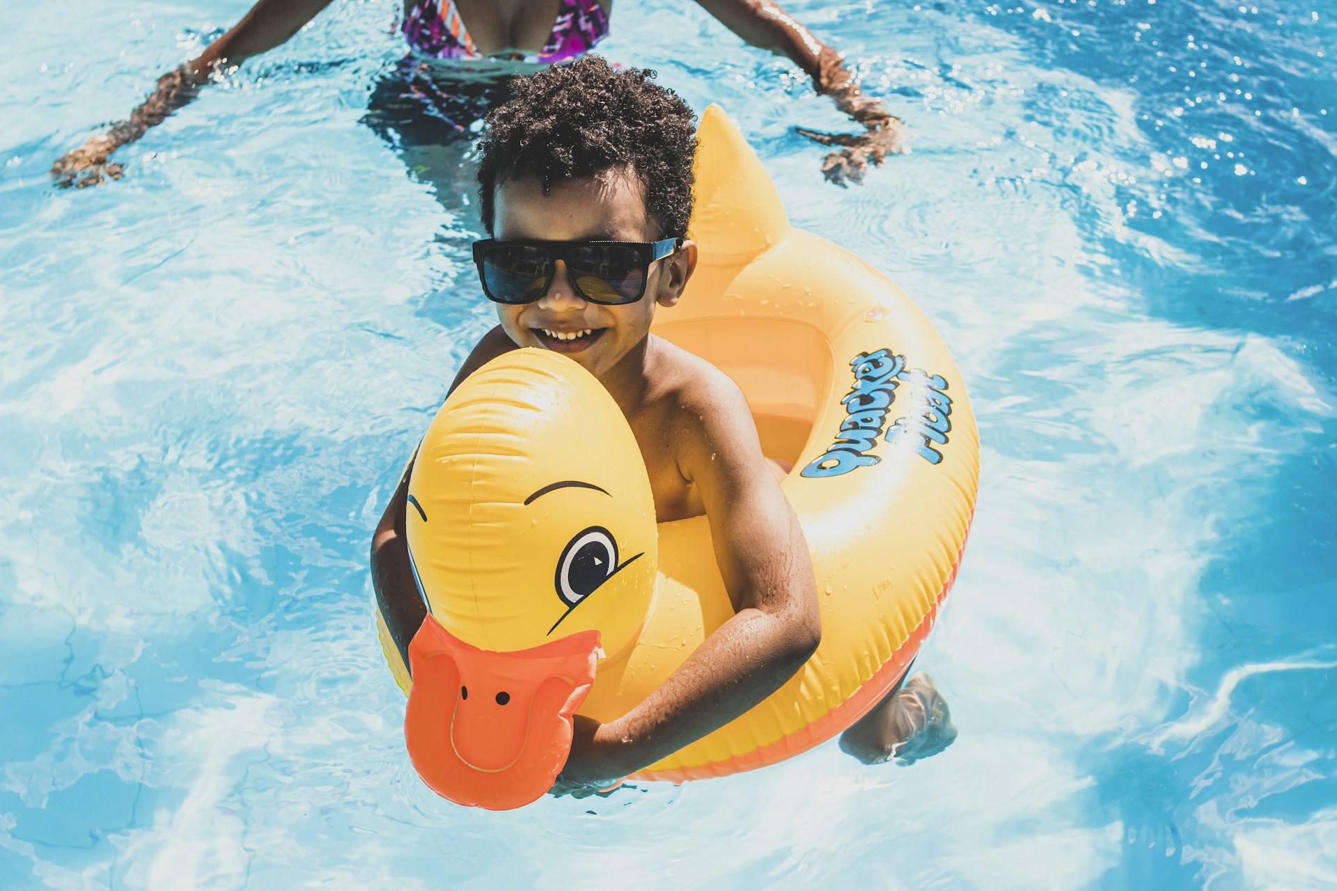 a boy in a swimming pool holding an inflatable ducky