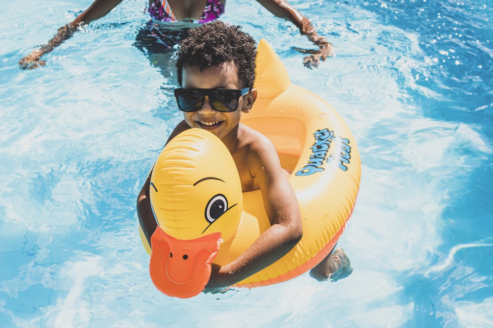 a boy in a swimming pool holding an inflatable ducky