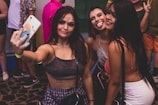A group of friends laughing and taking selfies at a party.