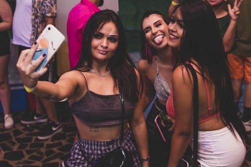 A group of friends laughing and taking selfies at a party.