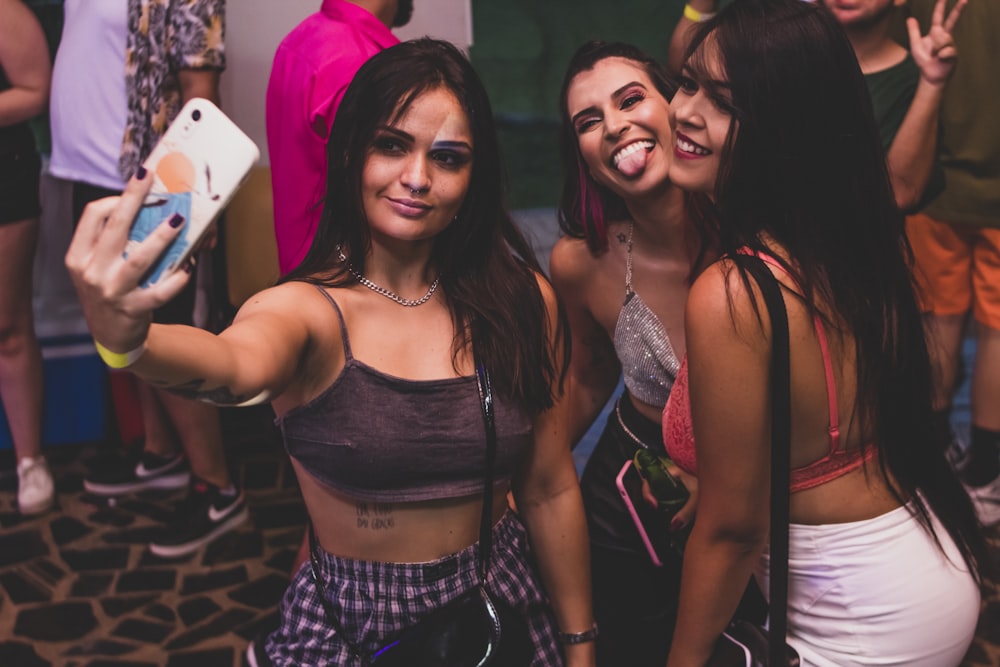 two girls taking a selfie in front of a group of people