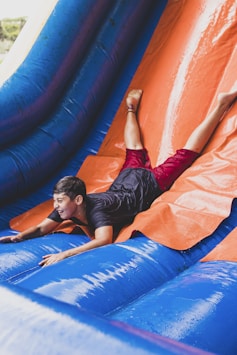 a young man sliding down an inflatable slide
