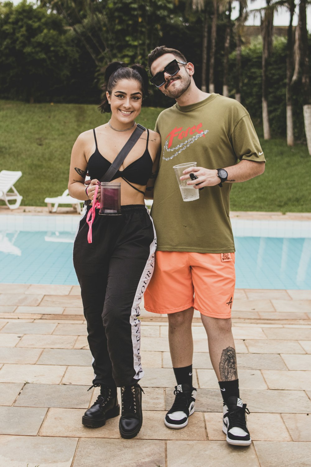 a man and a woman standing next to a swimming pool