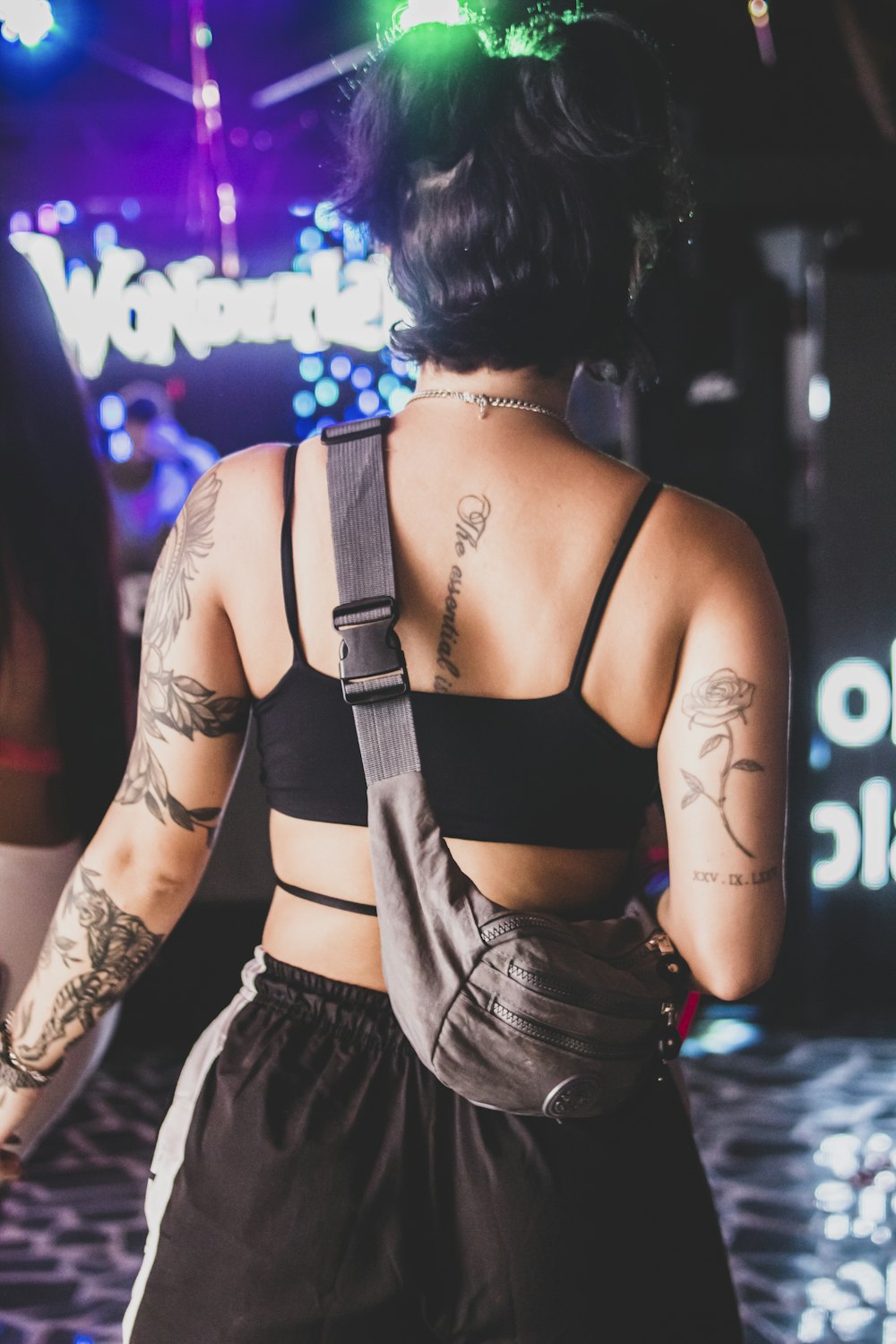 a woman with tattoos on her back standing in front of a stage