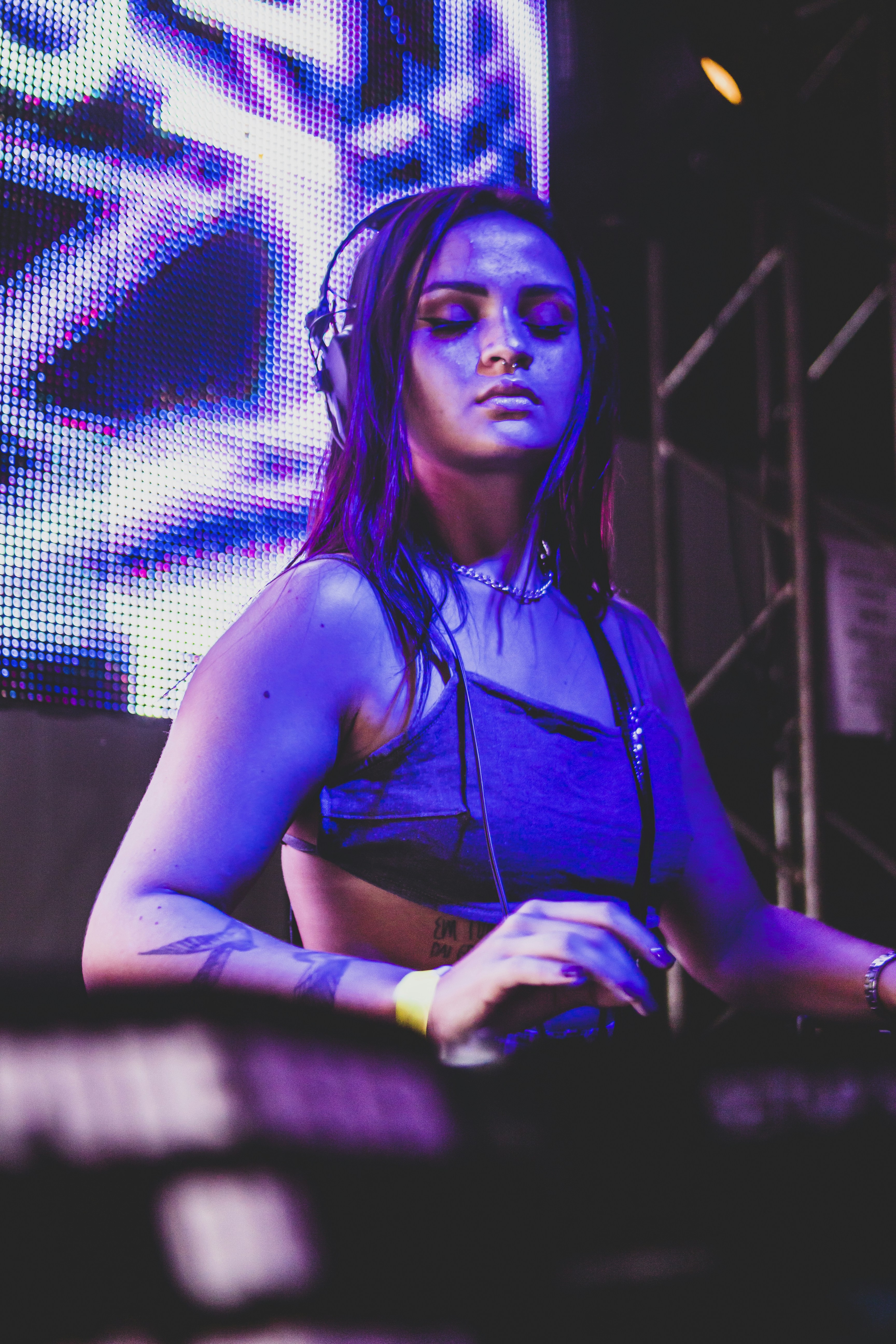 Female DJ with headphones in dark studio with purple neon lighting