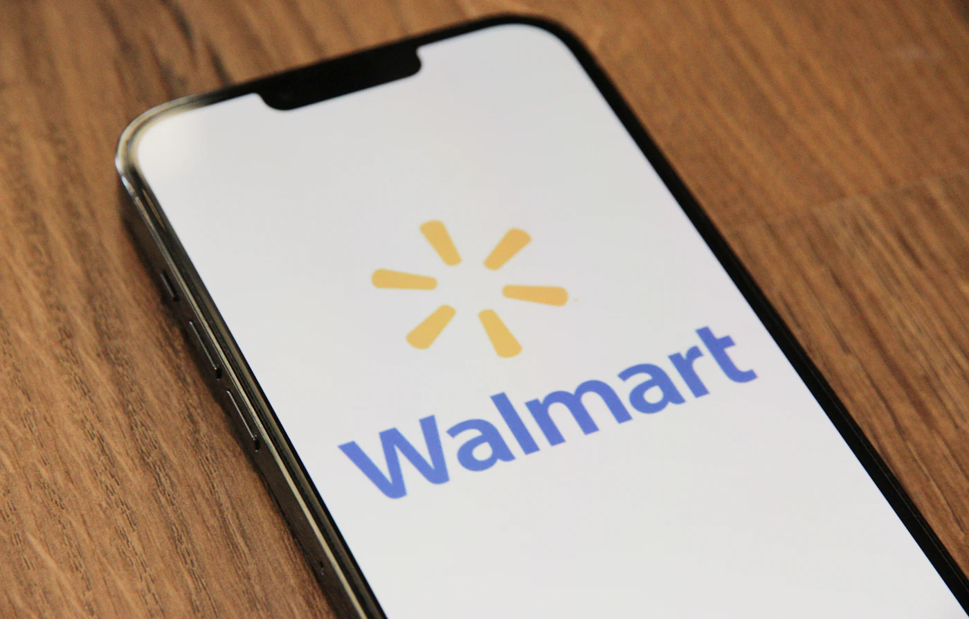 Smartphone on a wooden table displaying the Walmart logo