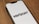 A smartphone lies on a wooden surface displaying the Verizon logo on its screen. The phone is positioned at an angle, showcasing the logo prominently against a white background.
