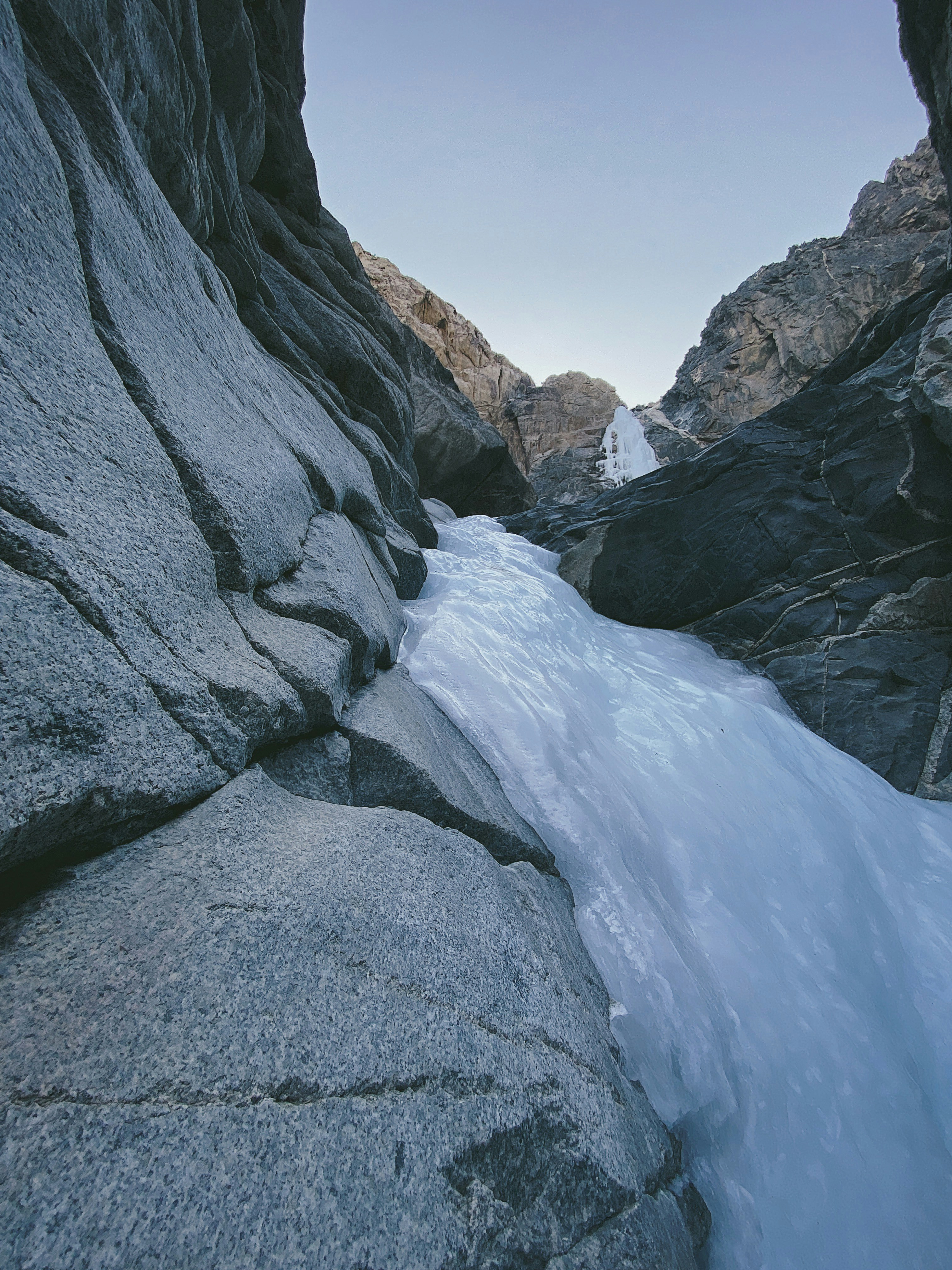 A frozen river running between two large rocks photo – Free Mountain ...