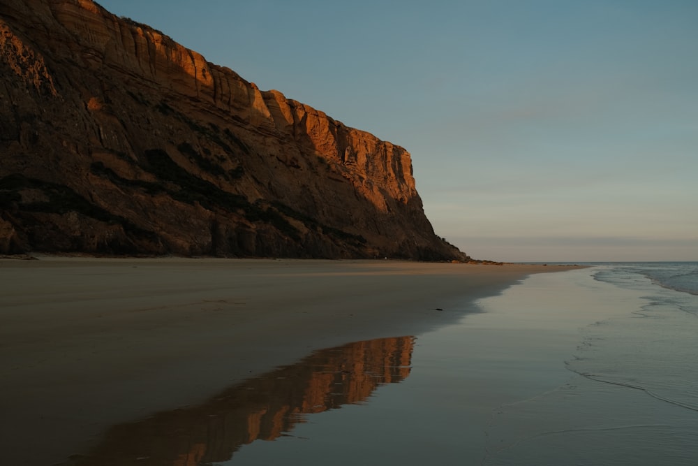 a sandy beach next to a large mountain