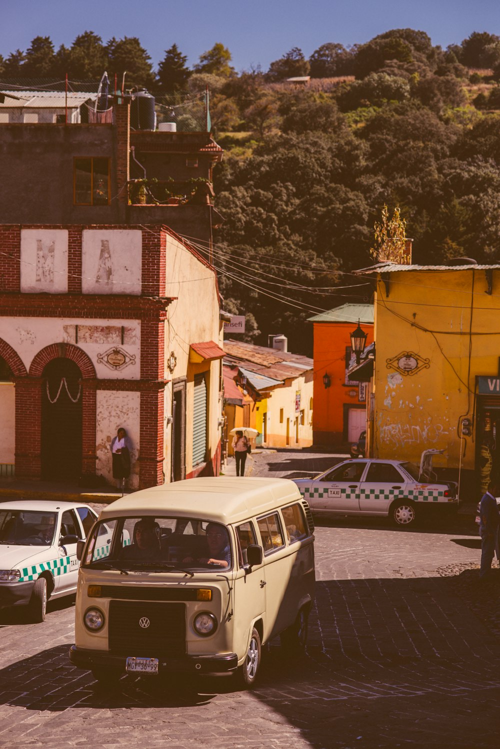 a small white van driving down a street next to tall buildings