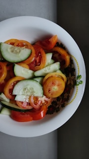 A colorful bowl of fresh salad with mixed greens, cherry tomatoes, and cucumber slices.