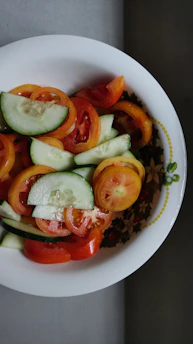 A colorful bowl of fresh mixed salad with vibrant greens, cherry tomatoes, and sliced cucumbers.