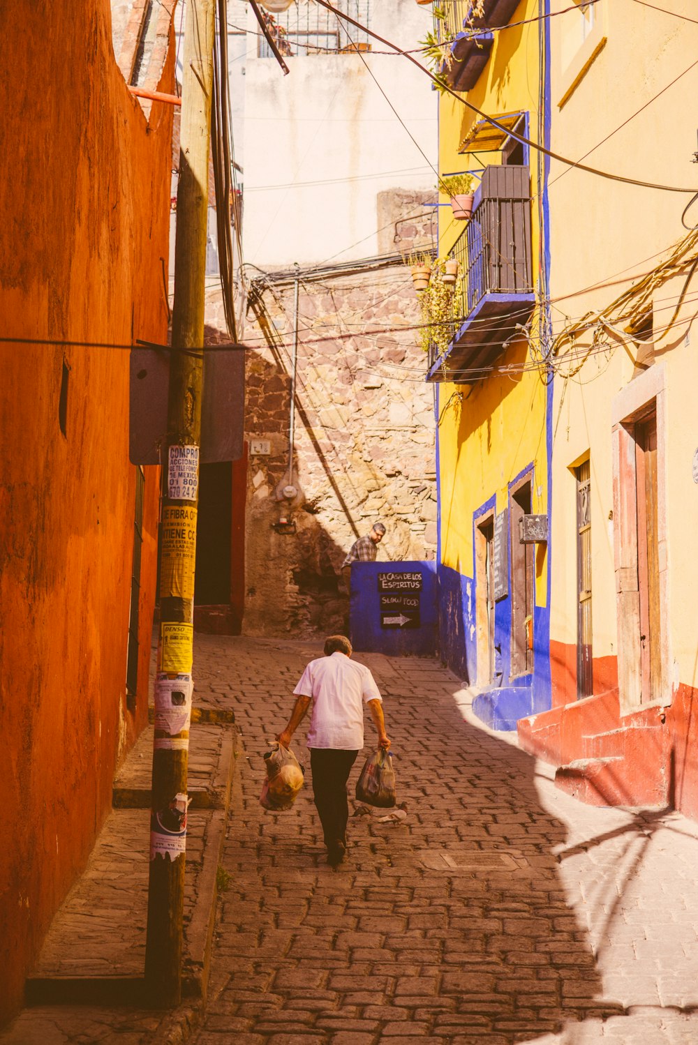 a man walking down a brick street next to a yellow building