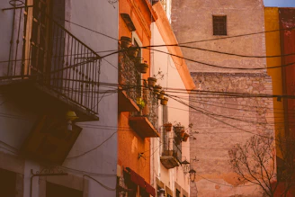 Golden hour light illuminating the intricate iron balconies and rustic doors of colonial homes.