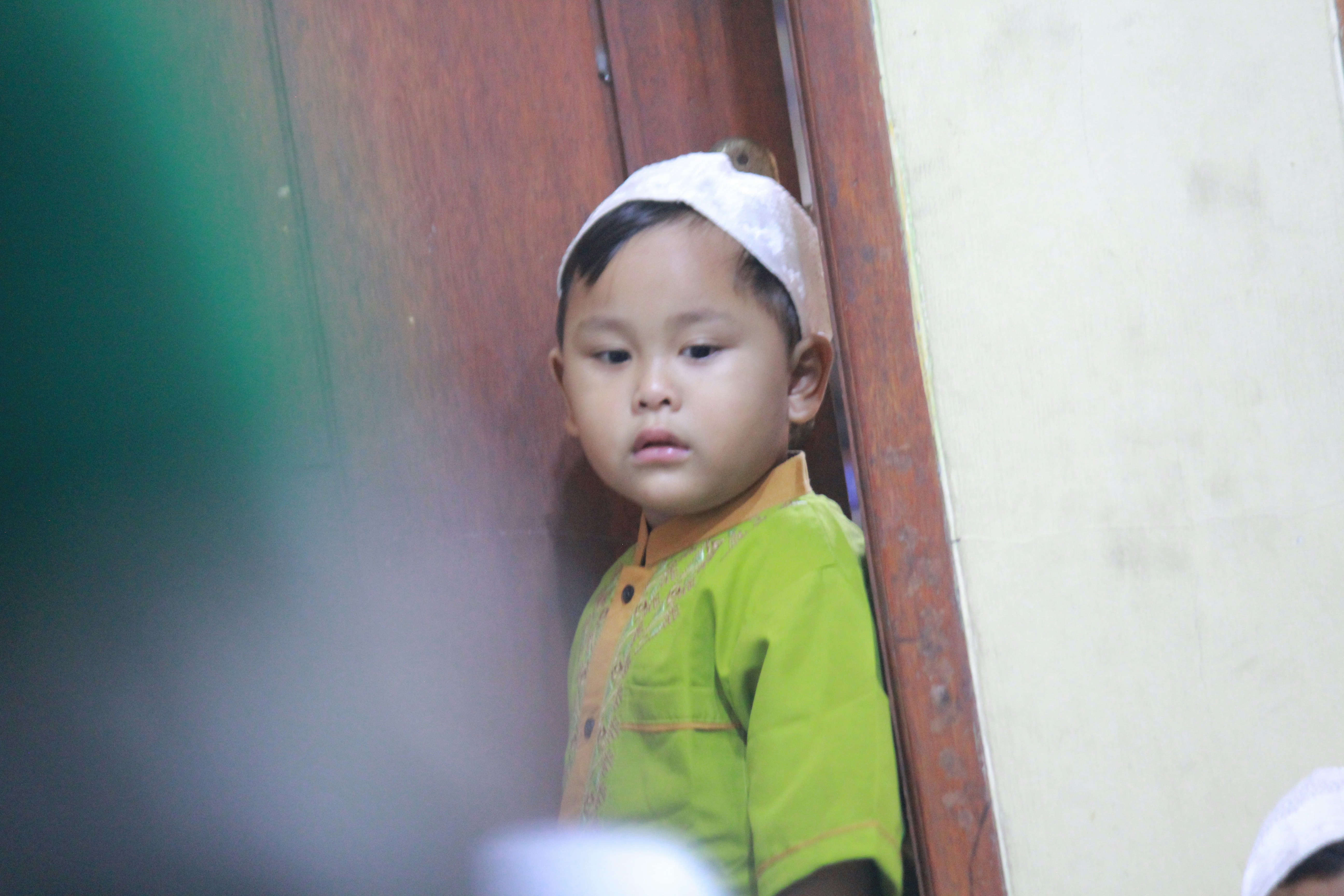 a little boy standing next to a wooden door