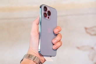 Close-up of a sleek mini smartphone held in a hand against a soft blurred background.