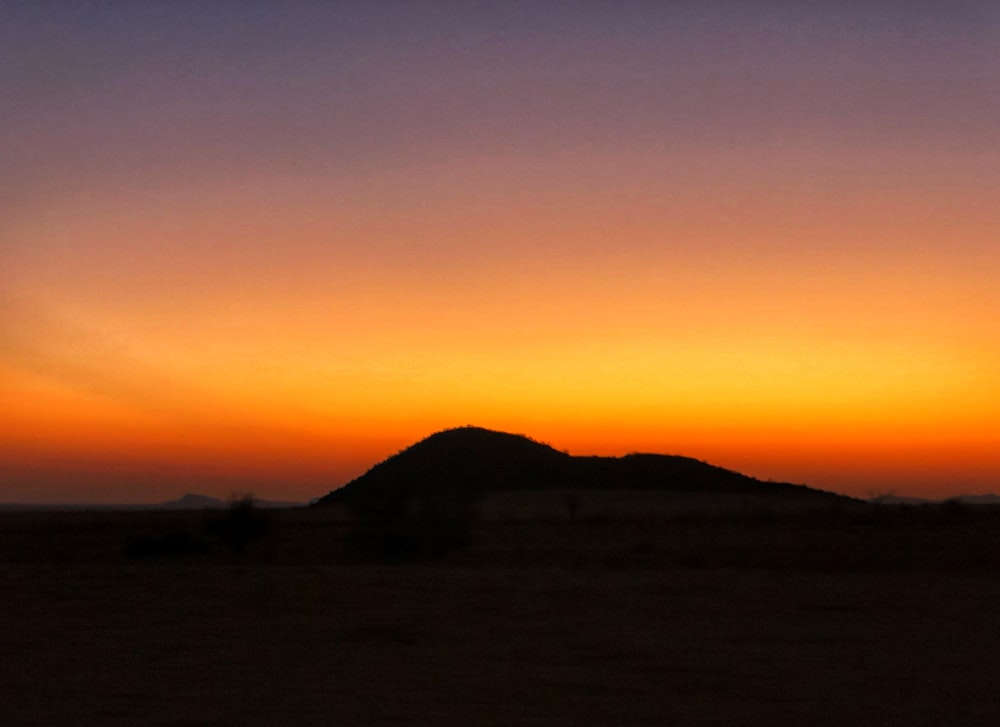 the sun is setting over a hill in the desert