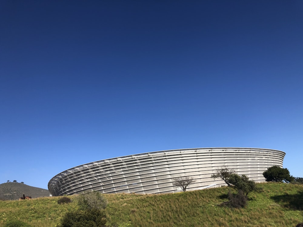 a large circular building sitting on top of a lush green hillside