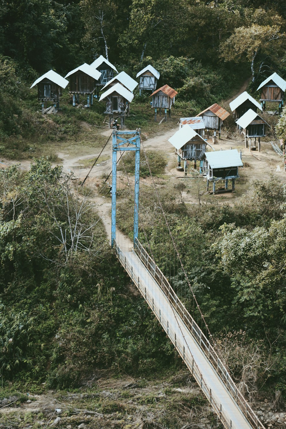 a suspension bridge over a small village in the woods