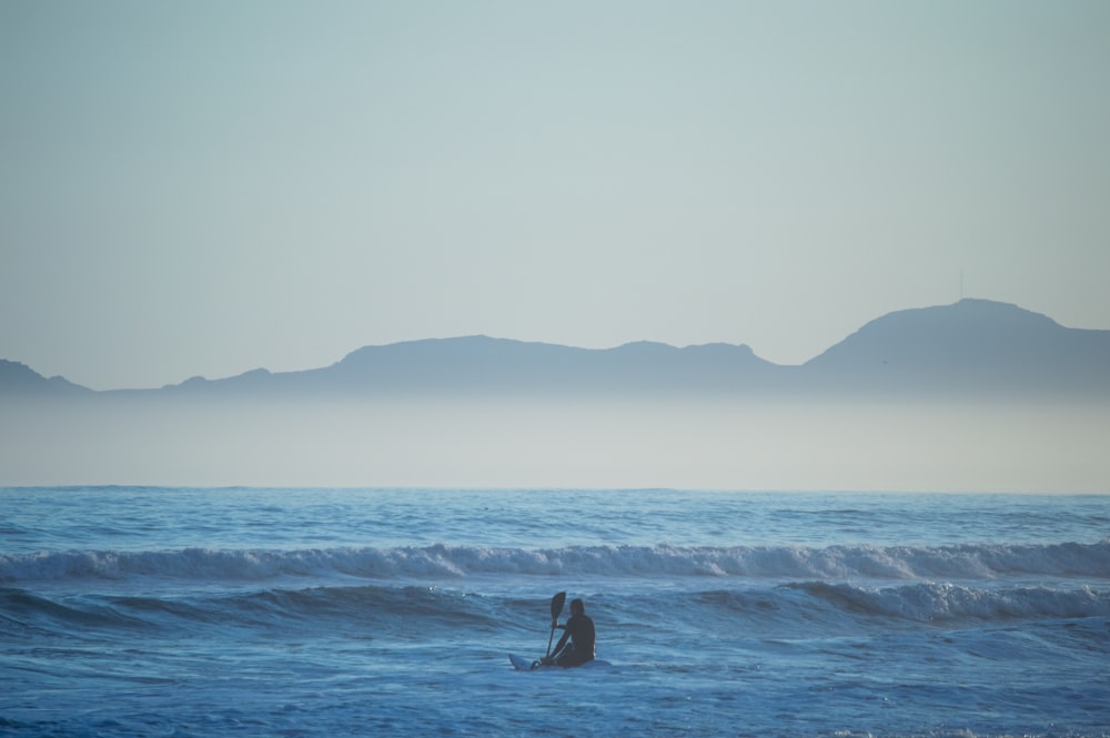 a couple of people standing on top of a wave in the ocean