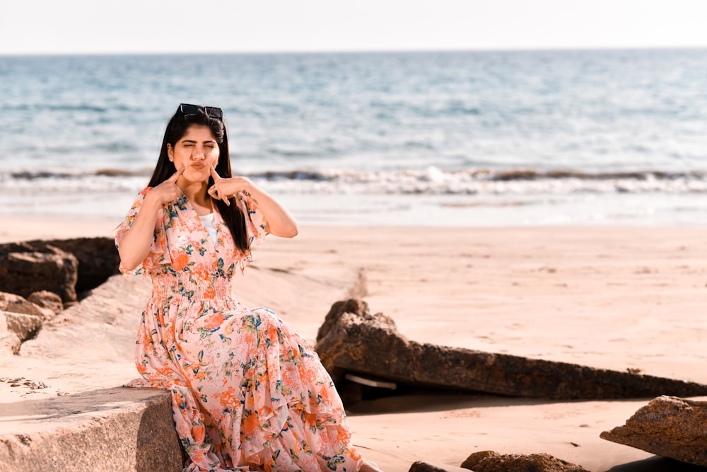 a woman sitting on a rock on the beach