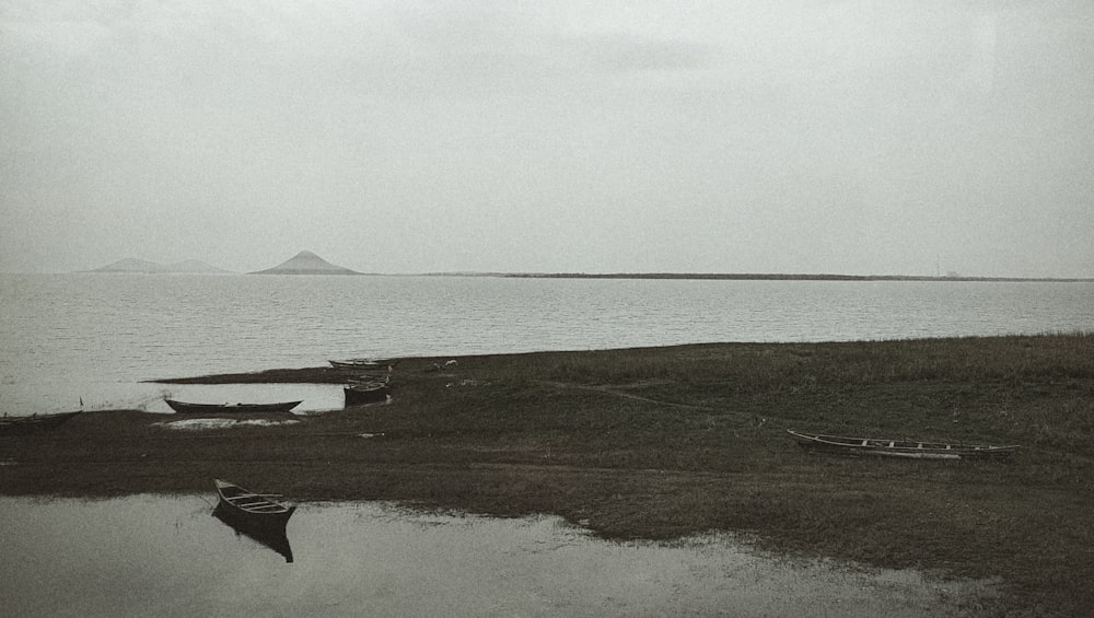 a black and white photo of boats on the shore