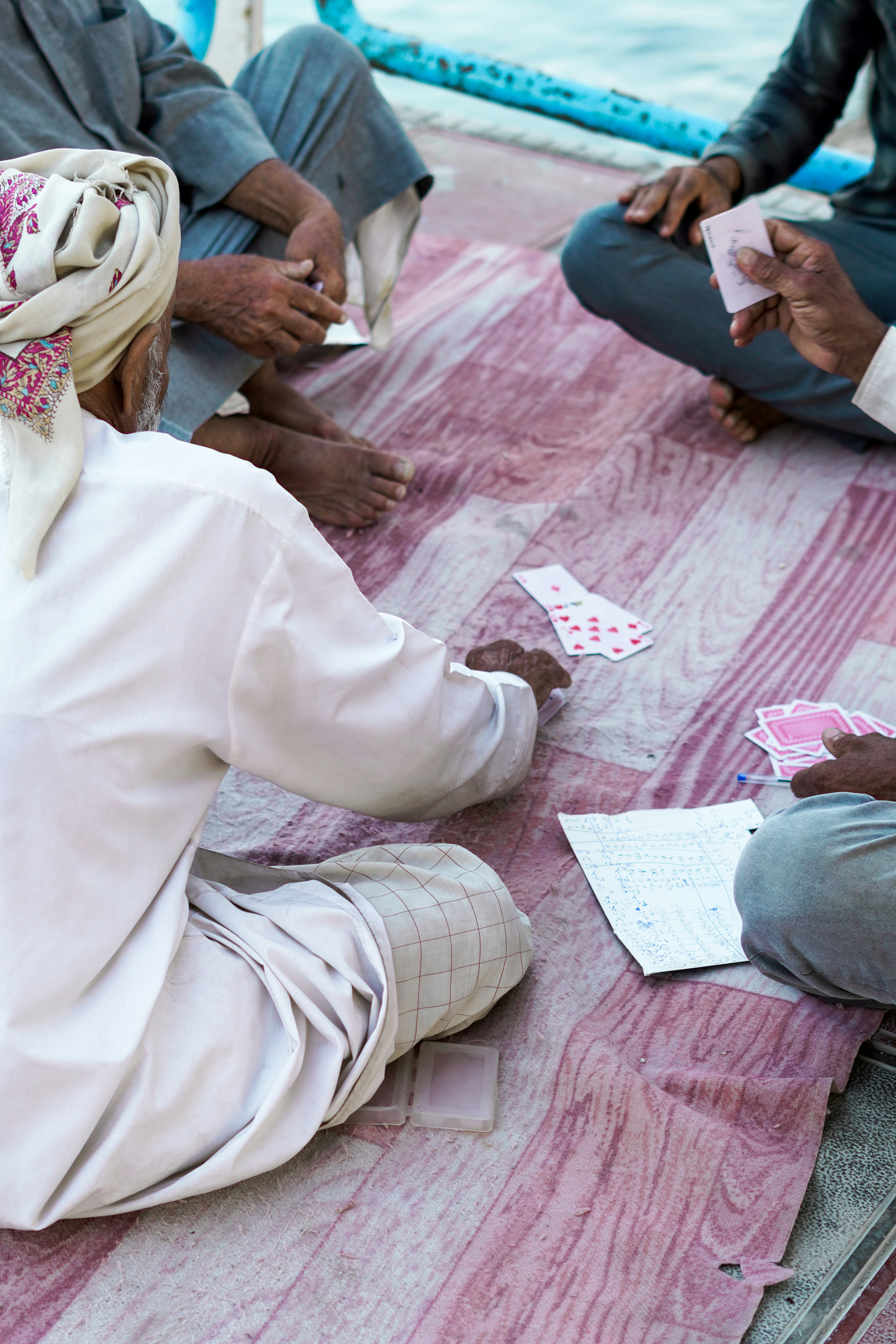 a group of people sitting on the ground playing cards
