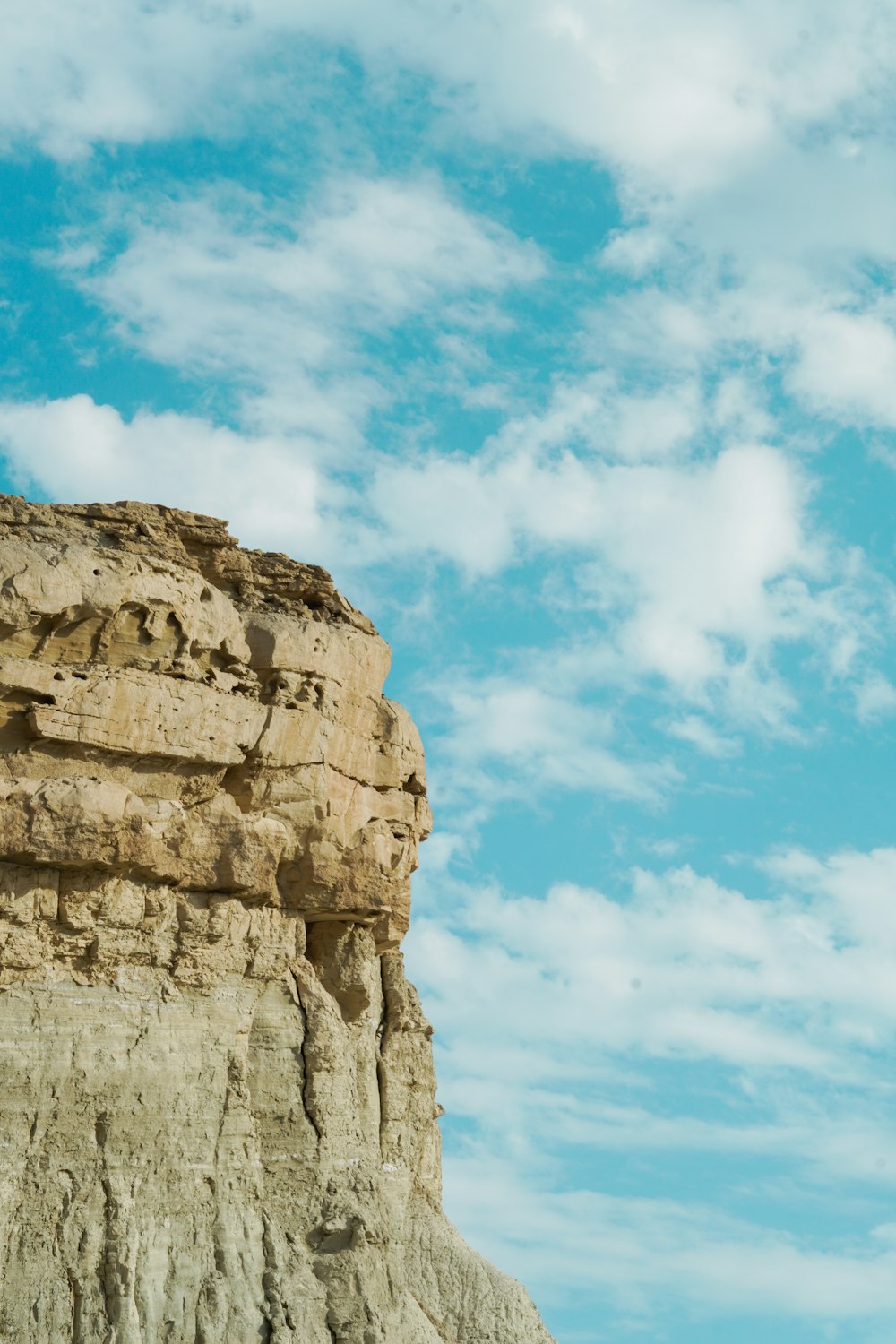 a man standing on top of a cliff under a blue sky