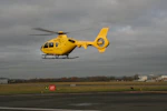 a yellow helicopter is flying low to the ground