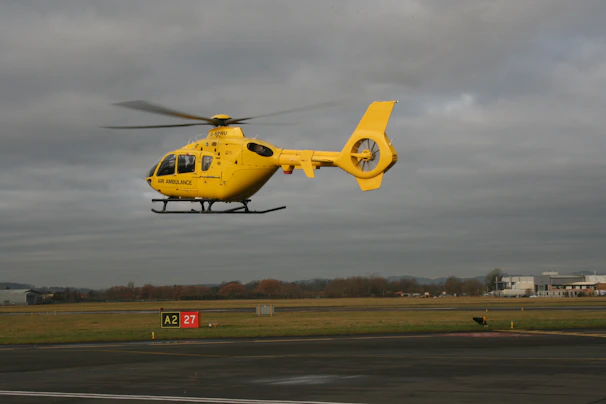 a yellow helicopter is flying low to the ground
