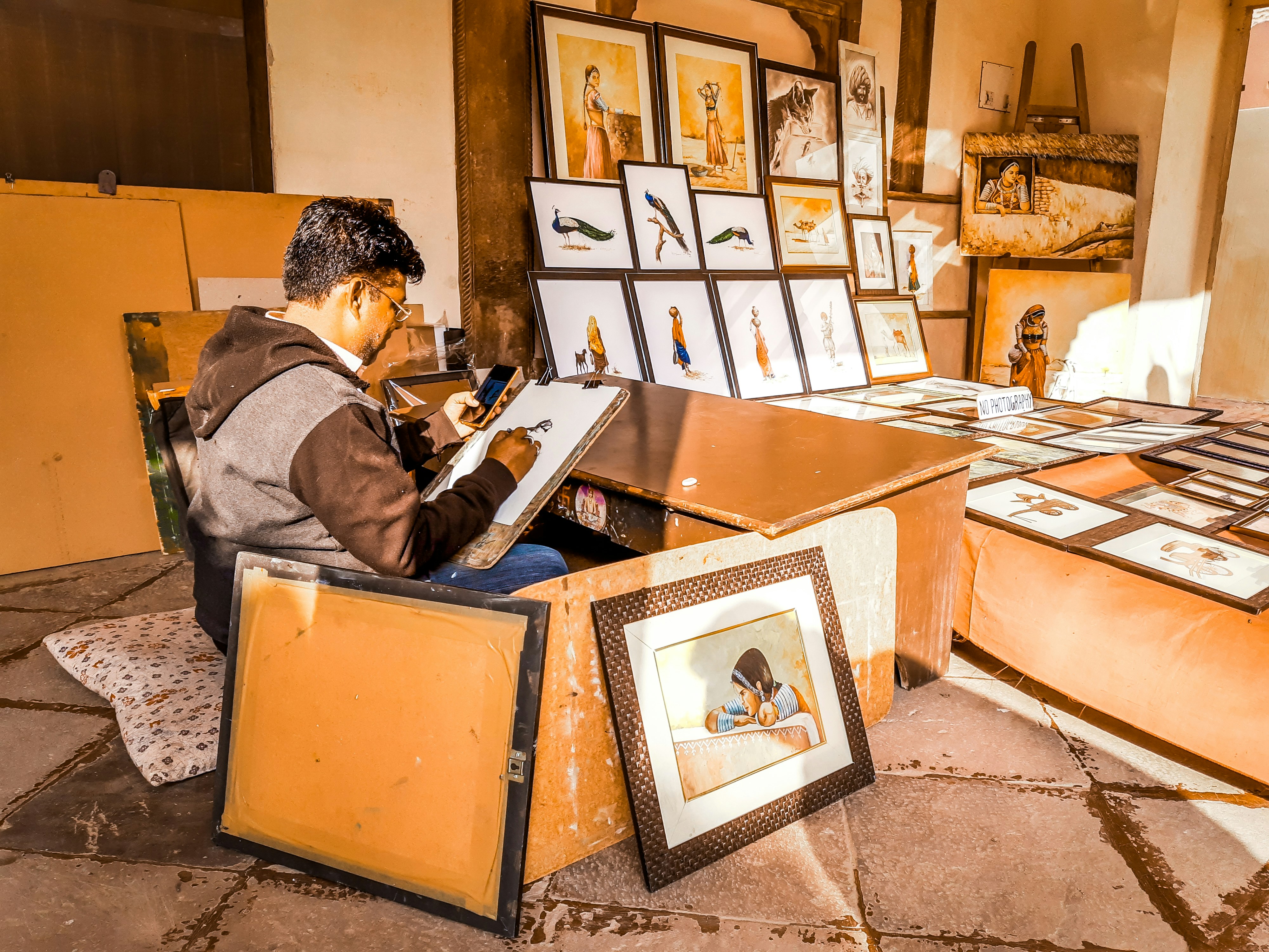 a man sitting at a desk in a room filled with pictures