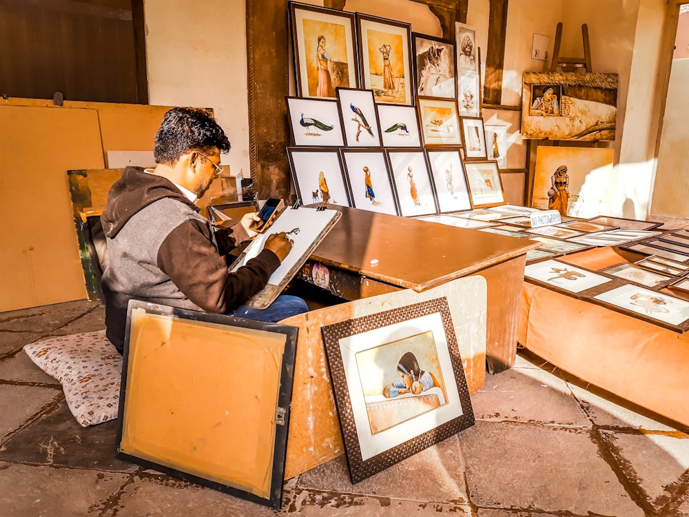 a man sitting at a desk in a room filled with pictures