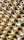Numerous metallic brass fittings are arranged in a pattern, showcasing their shiny and reflective surfaces. The fittings have a hexagonal shape with threaded ends, indicating they are likely used in plumbing or machinery. The close-up angle emphasizes their geometric forms and metallic luster.