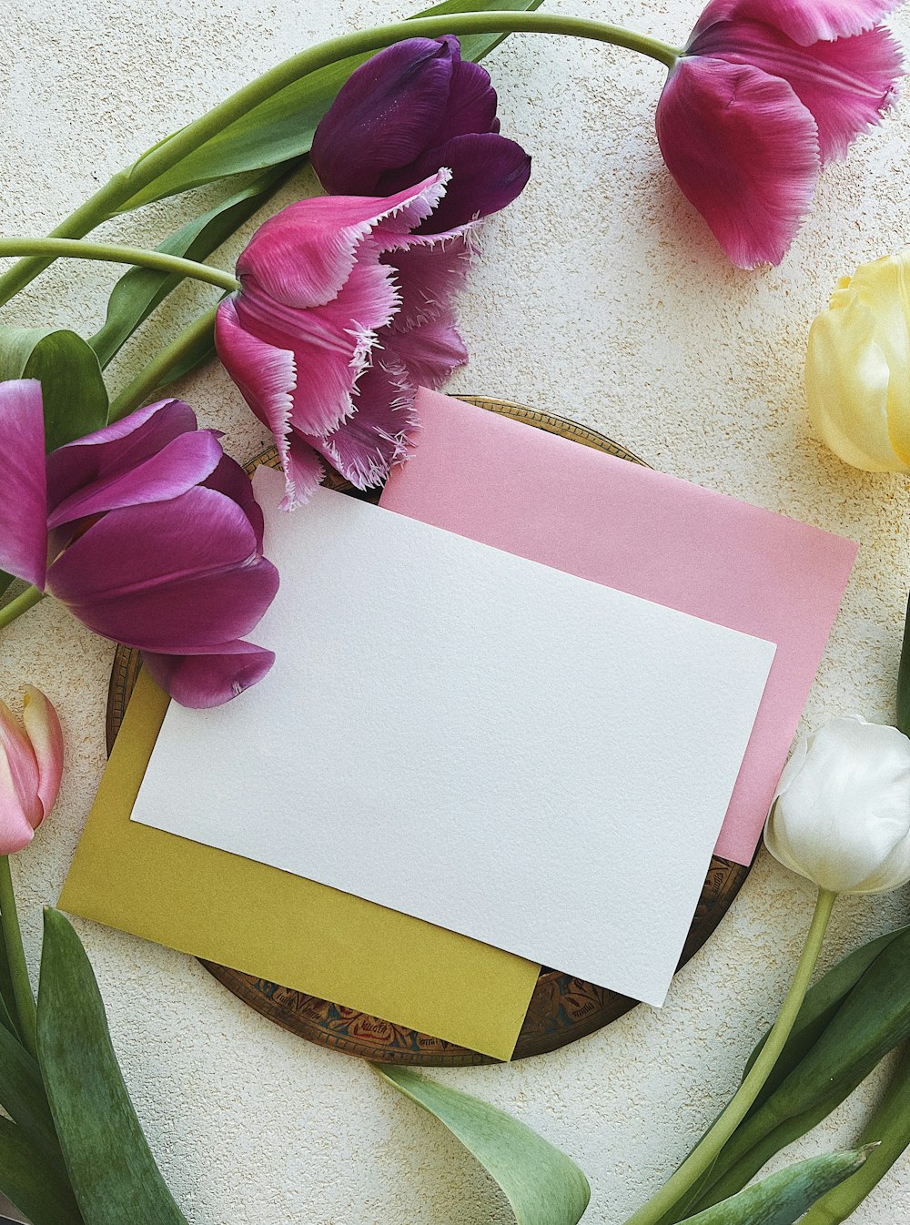a card with a blank paper surrounded by tulips