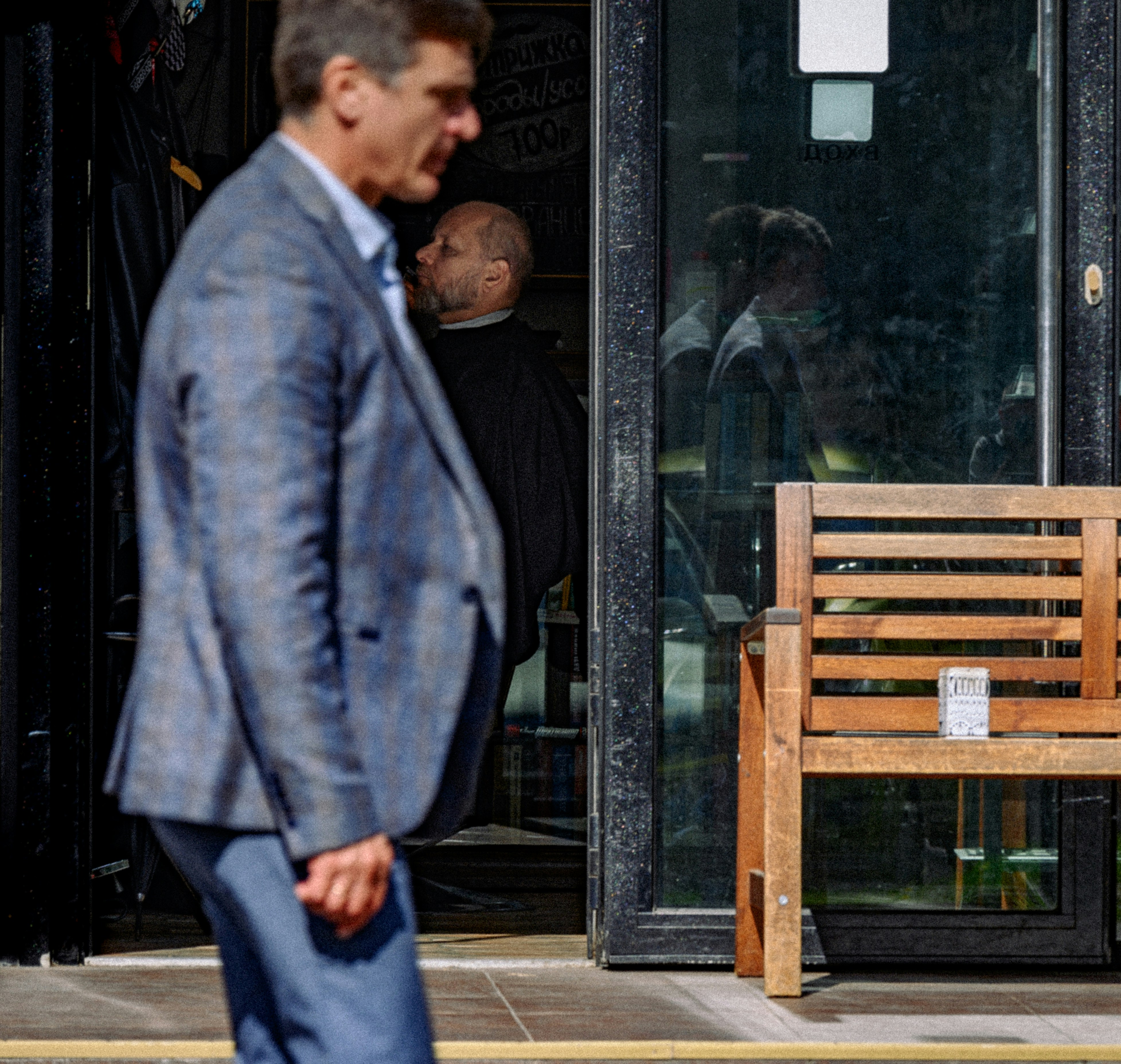 a man in a suit walking past a wooden bench